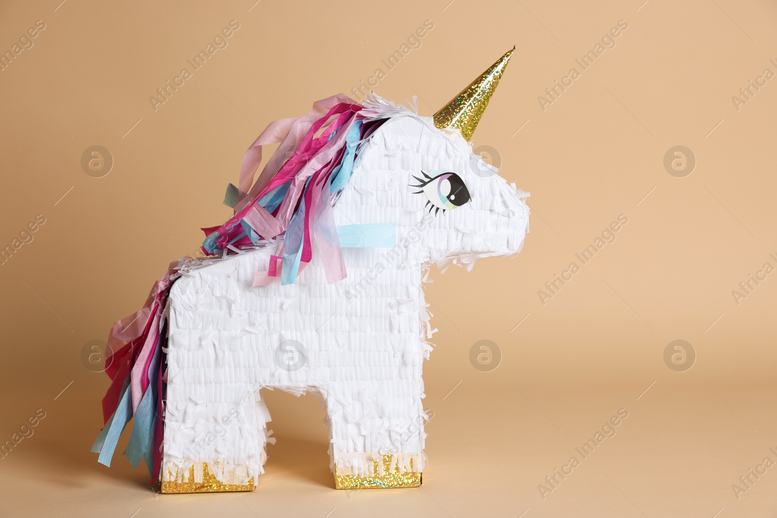 Photo of Unicorn shaped pinata on beige background, space for text