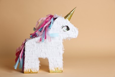 Photo of Unicorn shaped pinata on beige background, space for text