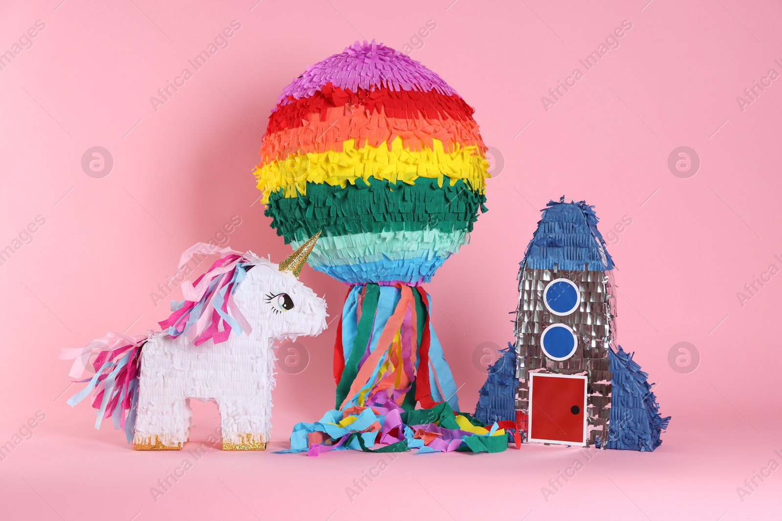 Photo of Different bright colorful pinatas on pink background