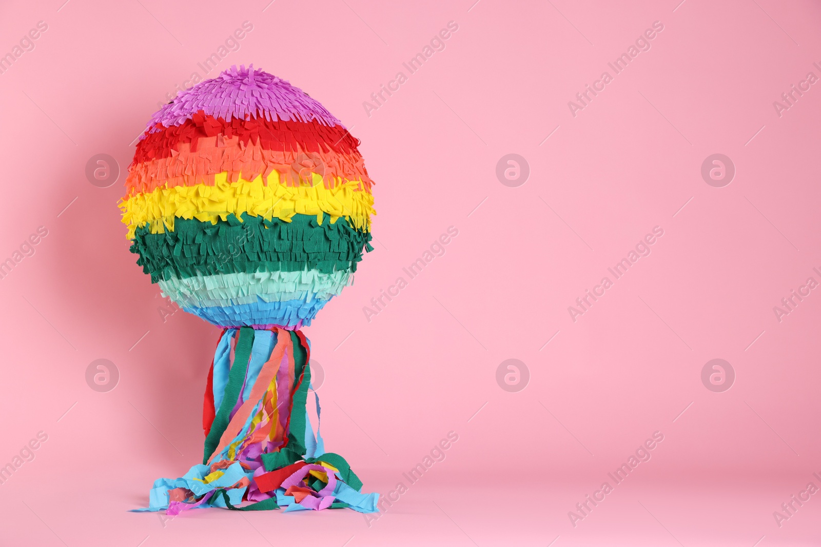 Photo of Colorful pinata on pink background, space for text