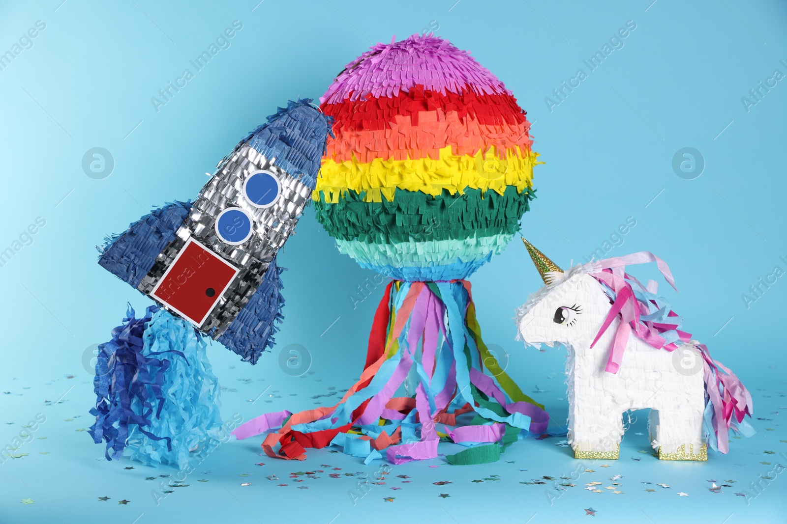 Photo of Different colorful pinatas and confetti on light blue background