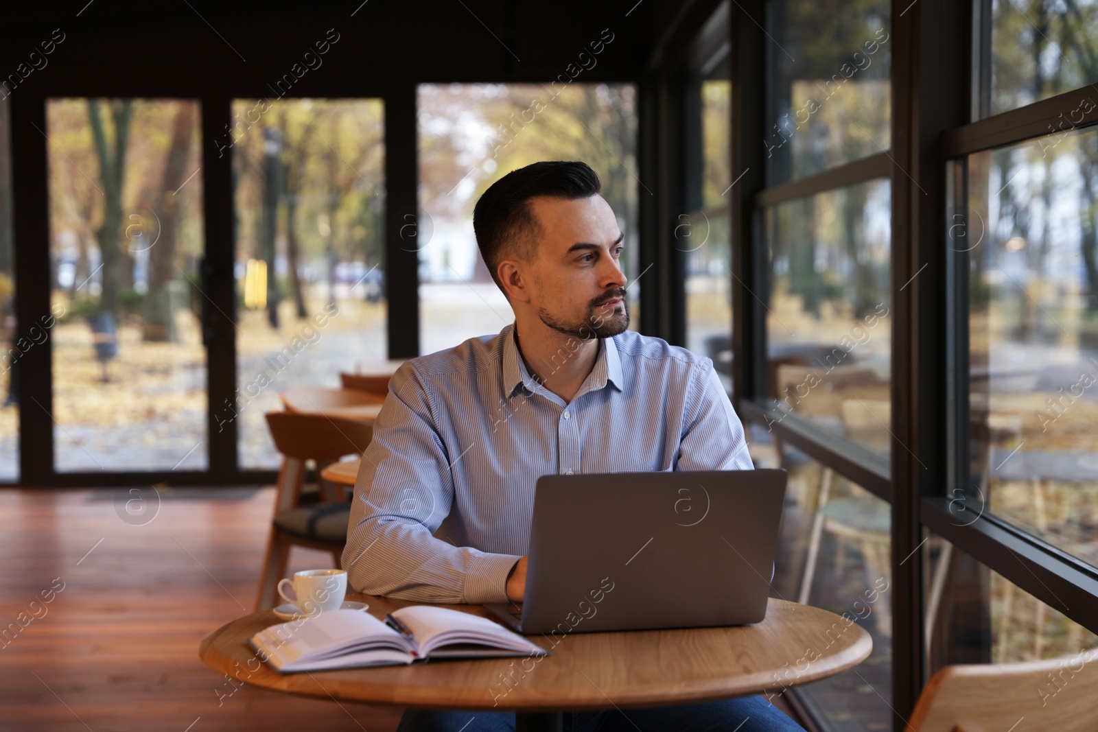 Photo of Man working on laptop at table in cafe