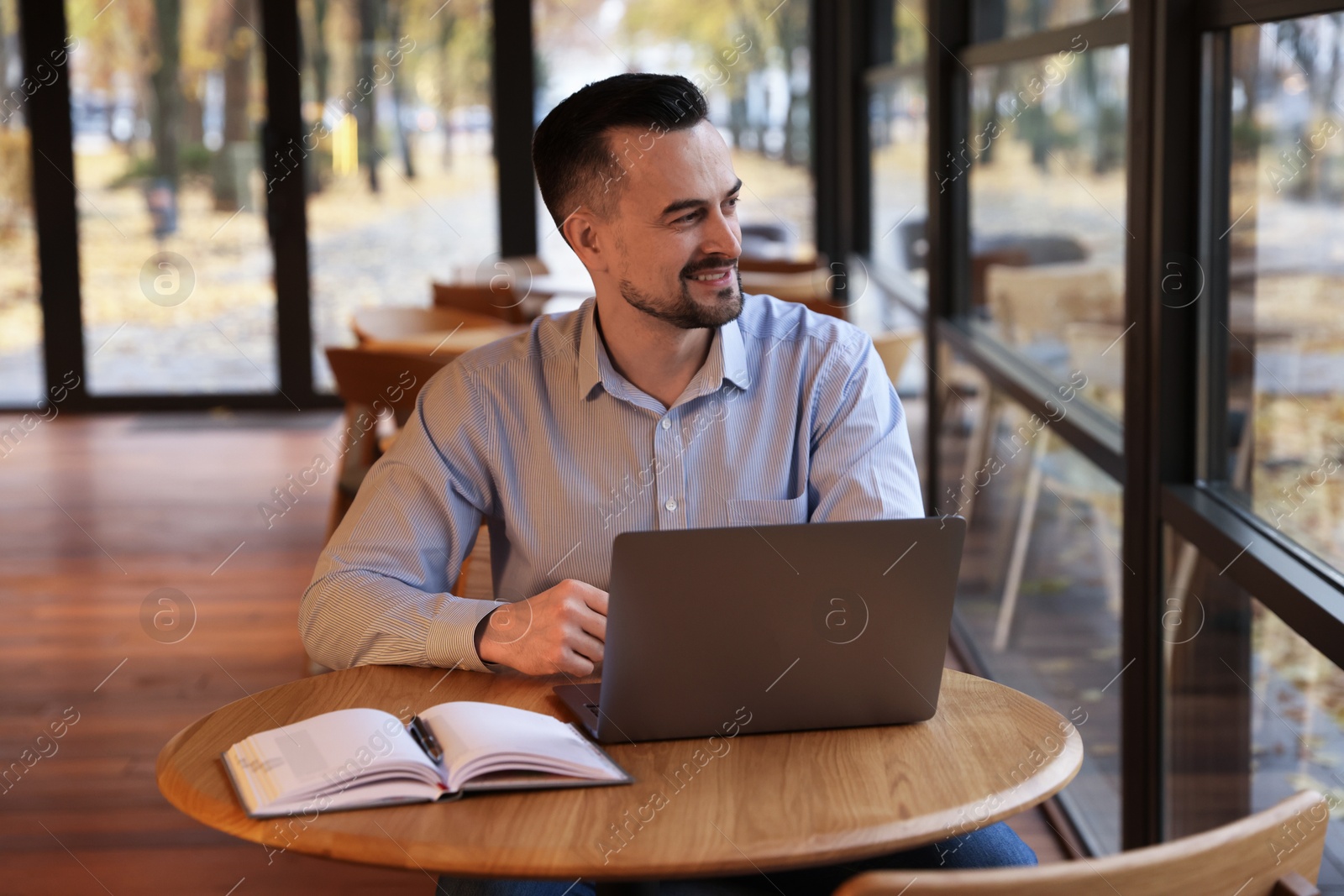 Photo of Man with laptop at table in cafe