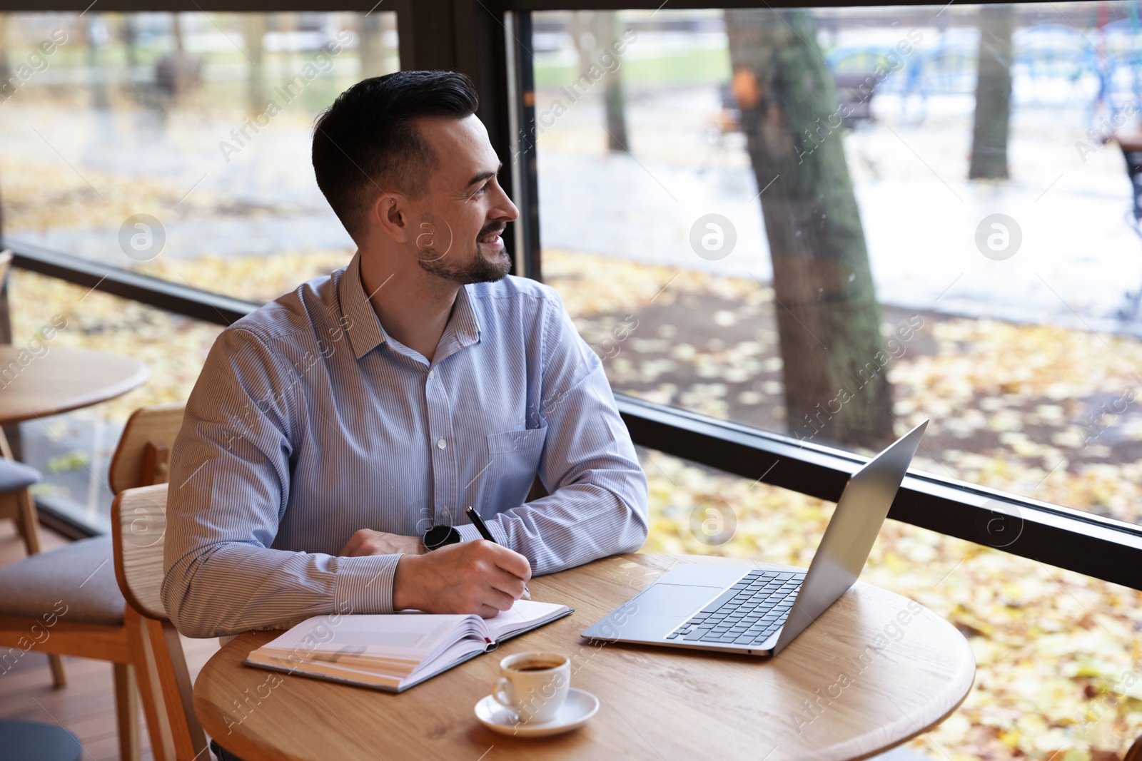 Photo of Man taking notes at table in cafe