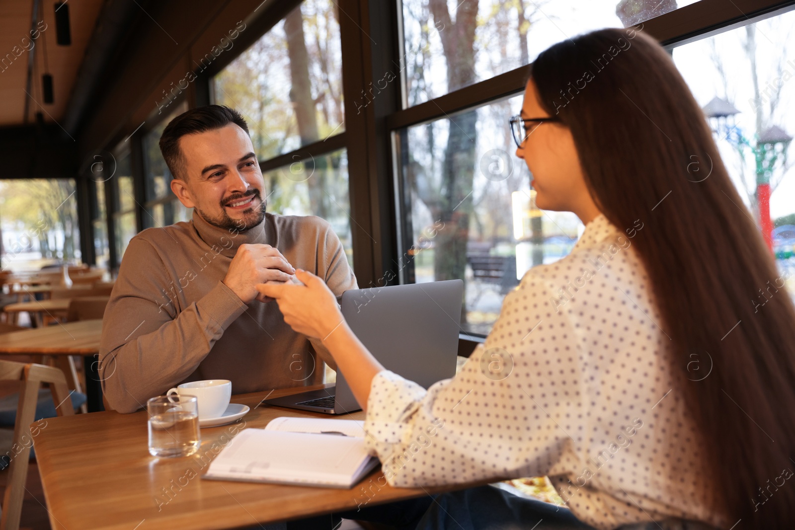 Photo of Colleagues working together at table in cafe