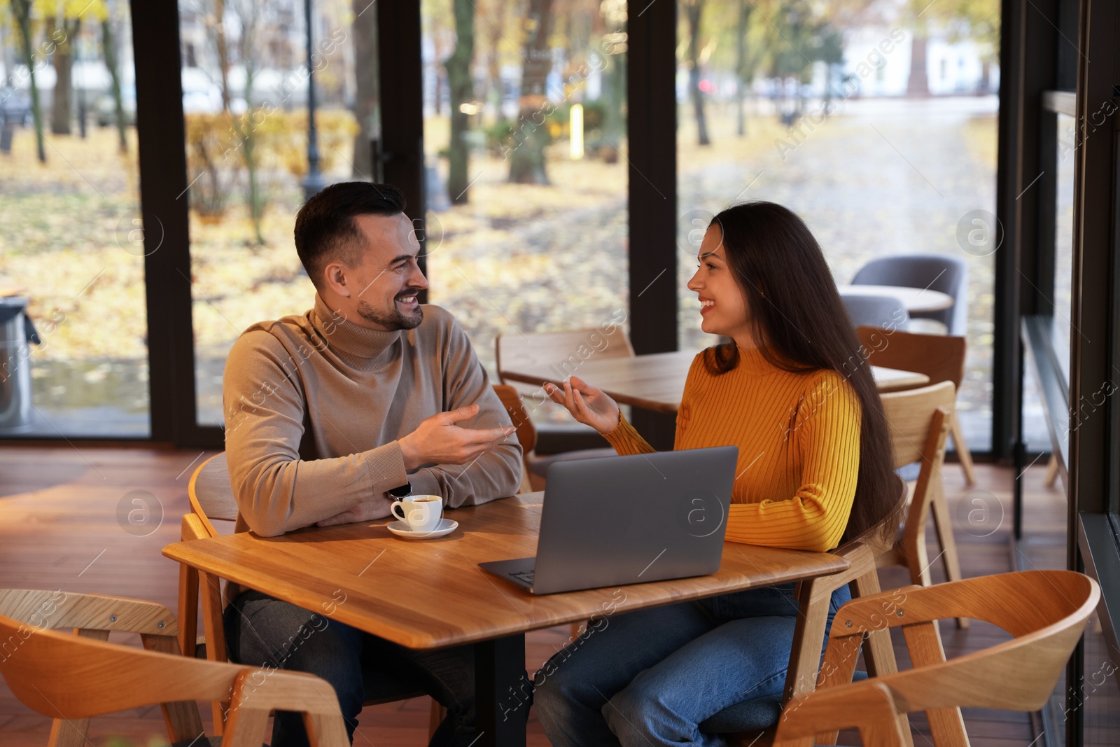 Photo of Colleagues with laptop working together at table in cafe