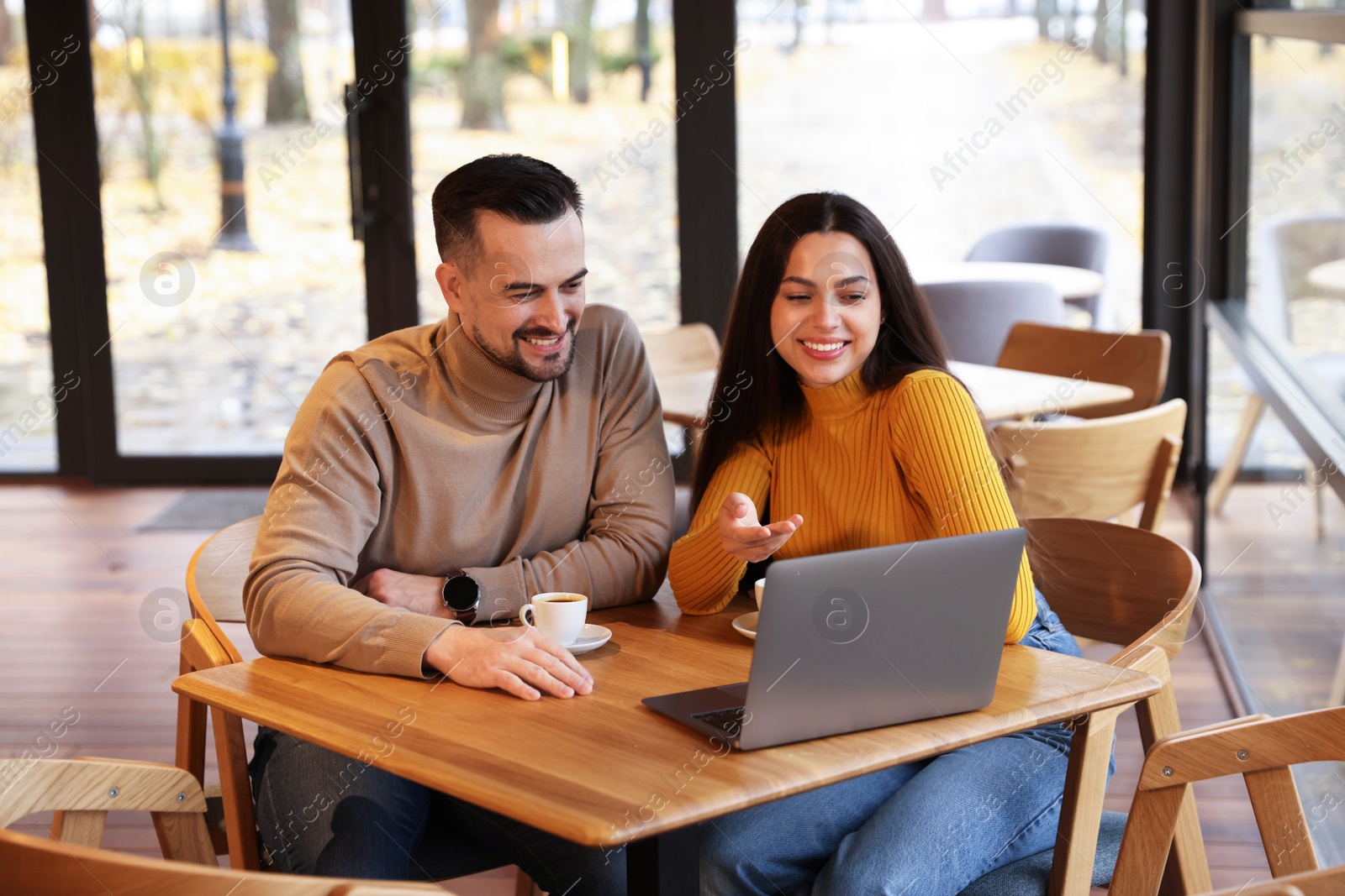 Photo of Colleagues with laptop working together at table in cafe