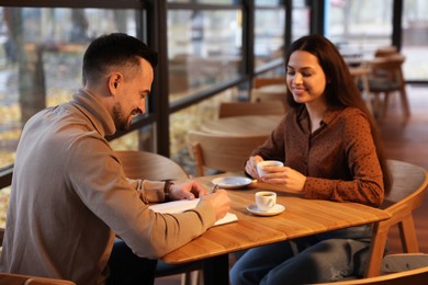 Photo of Colleagues working together at table in cafe