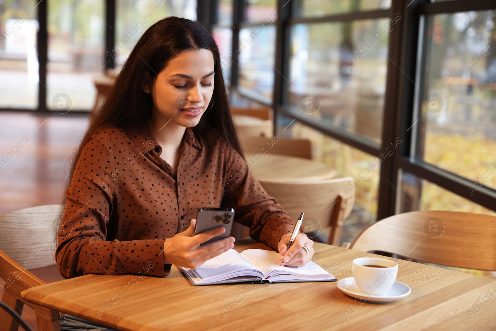 Photo of Woman using smartphone while working at table in cafe, space for text