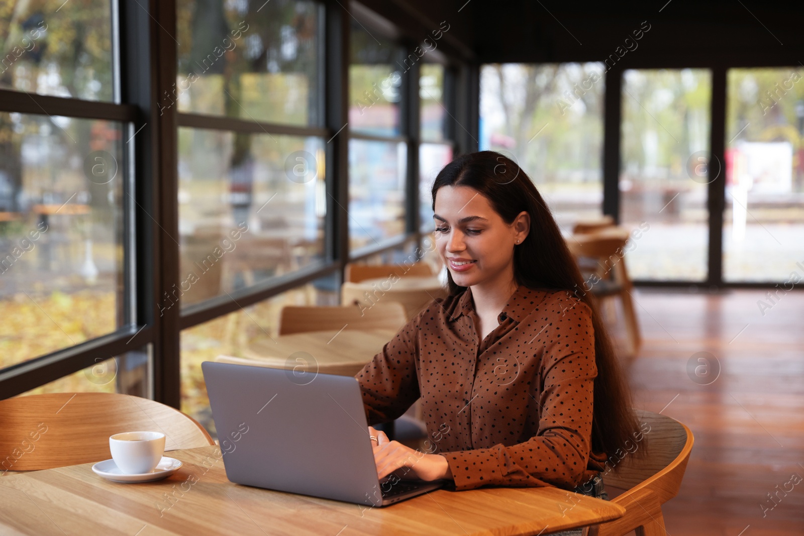 Photo of Woman working on laptop at table in cafe