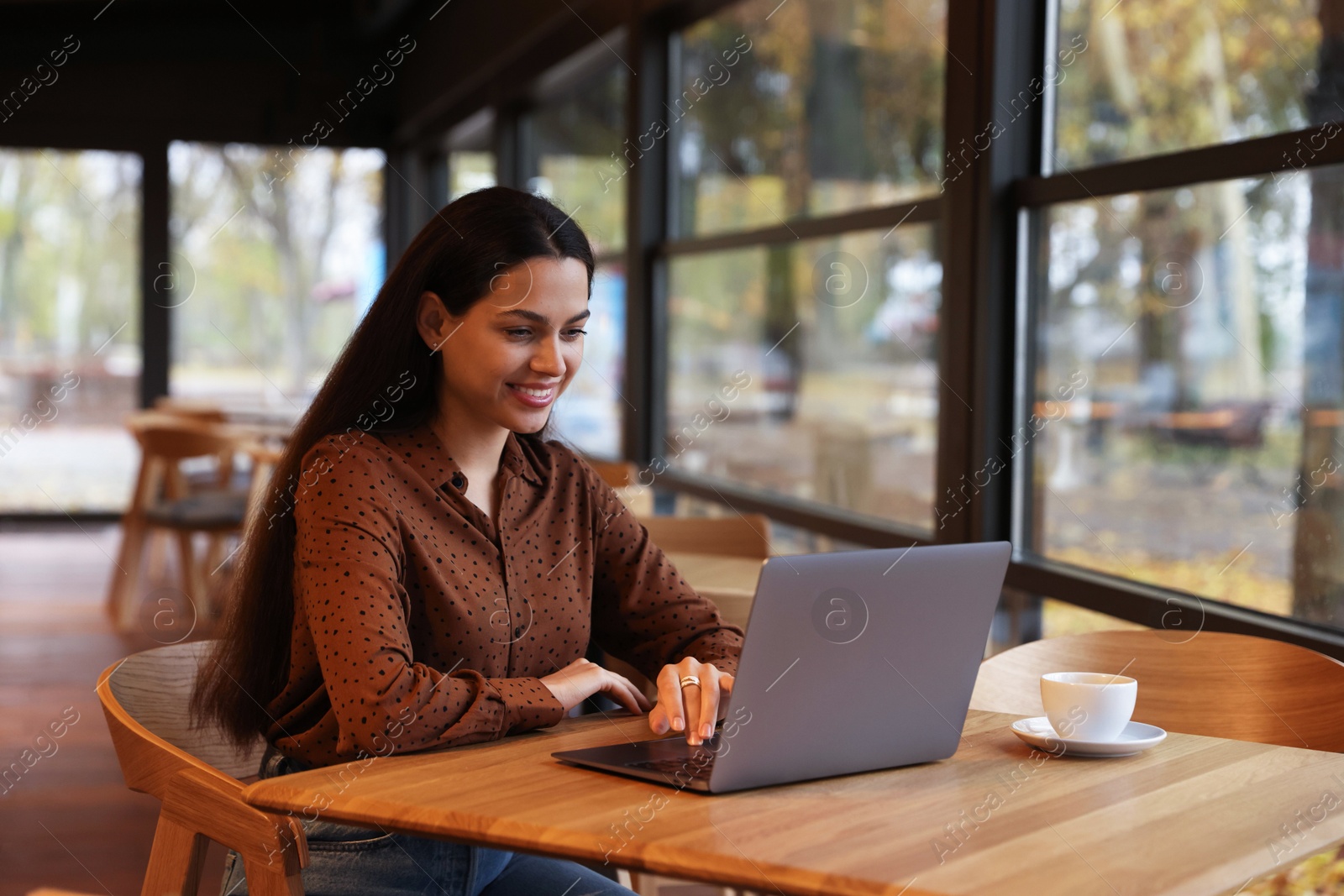 Photo of Woman working on laptop at table in cafe