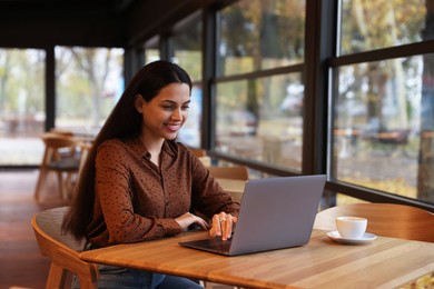 Photo of Woman working on laptop at table in cafe