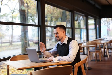 Man having video chat via laptop at table in cafe