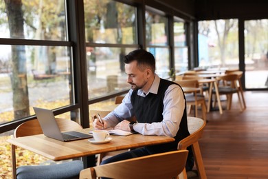 Man taking notes at table in cafe