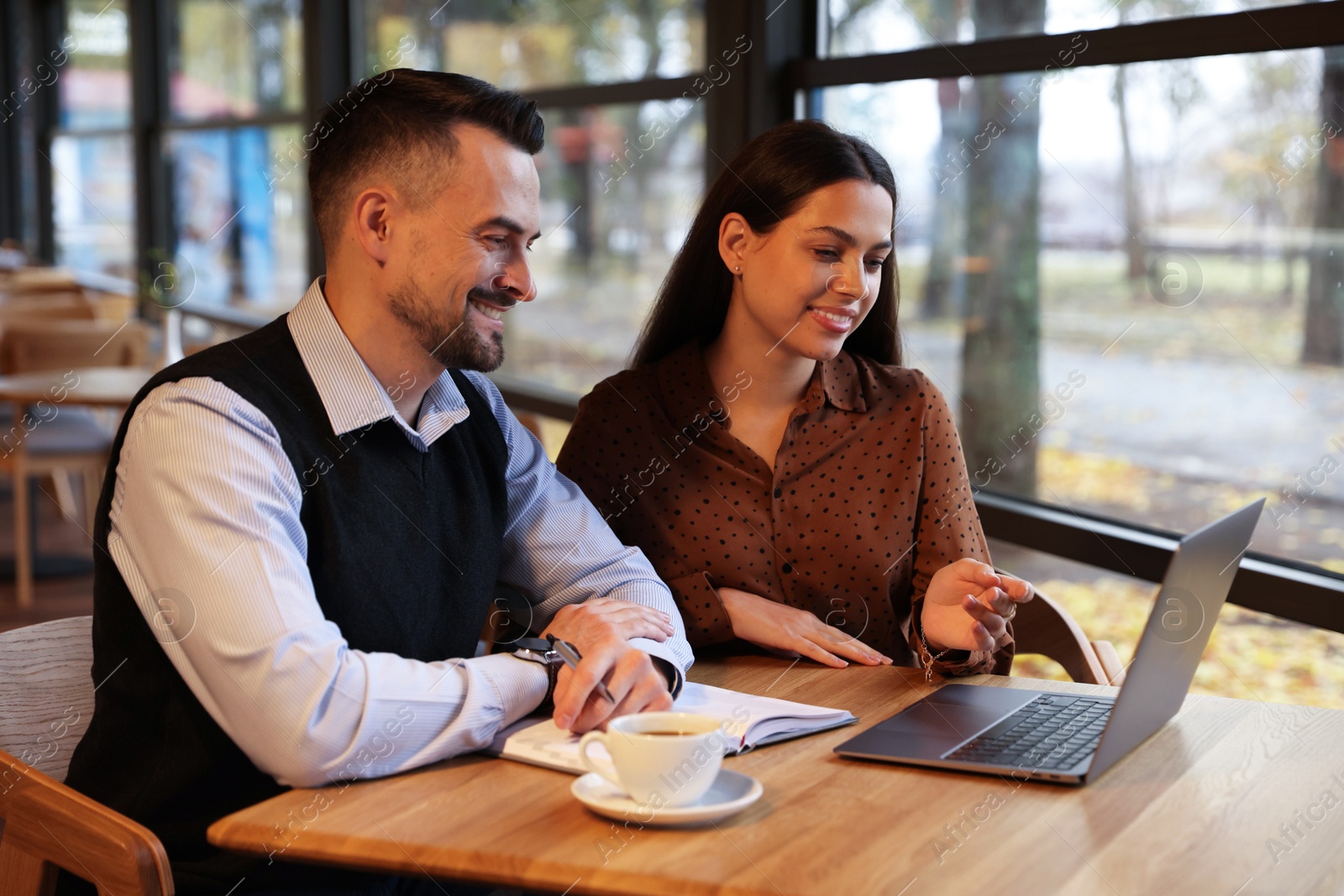 Photo of Colleagues with laptop working together in cafe