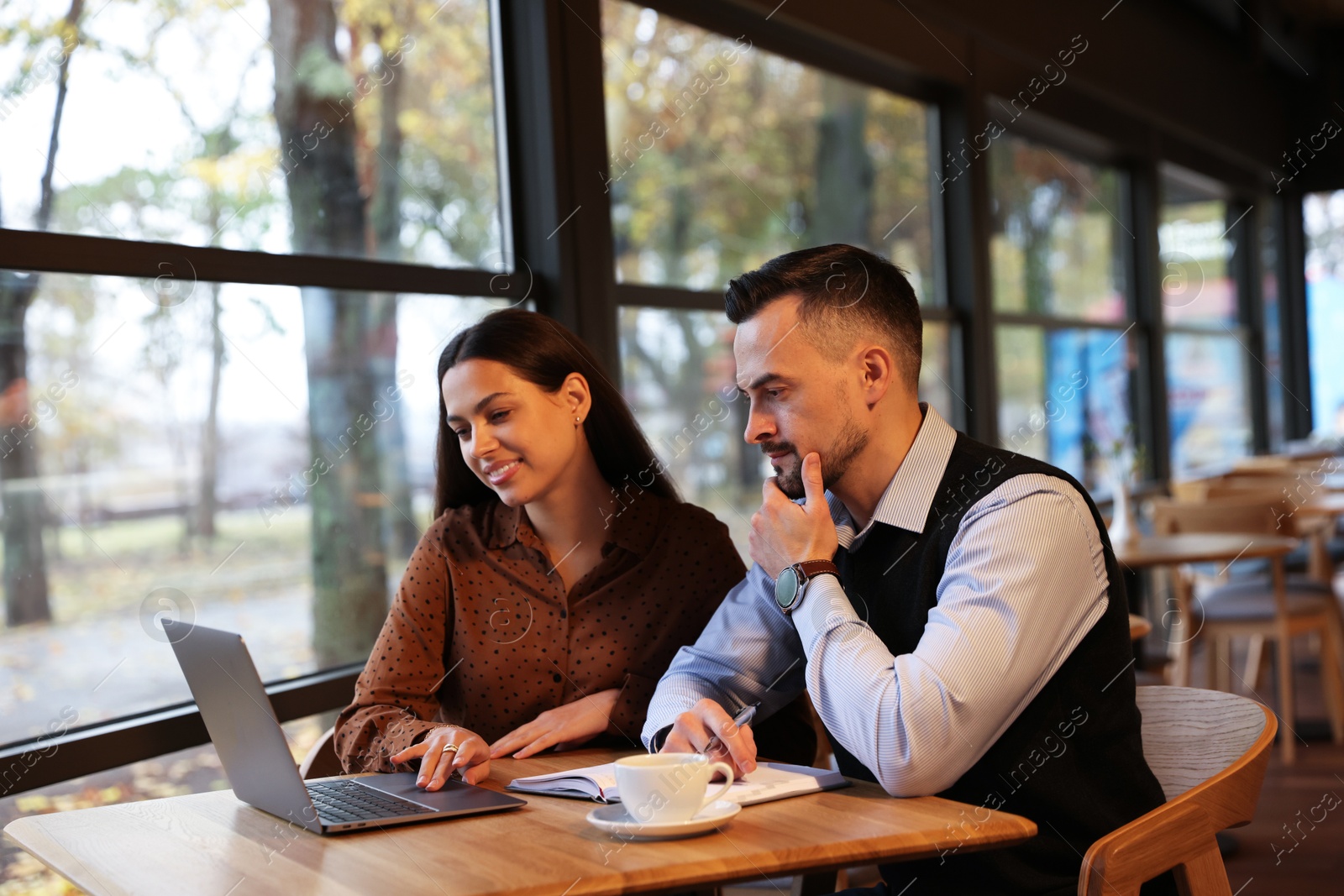 Photo of Colleagues with laptop working together in cafe