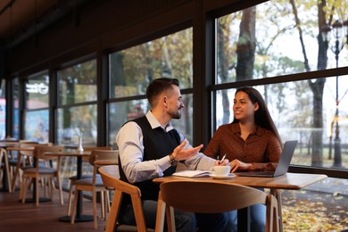 Colleagues with laptop working together in cafe