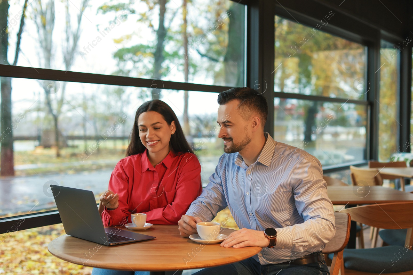 Photo of Colleagues with laptop working together in cafe