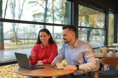 Photo of Colleagues with laptop working together in cafe