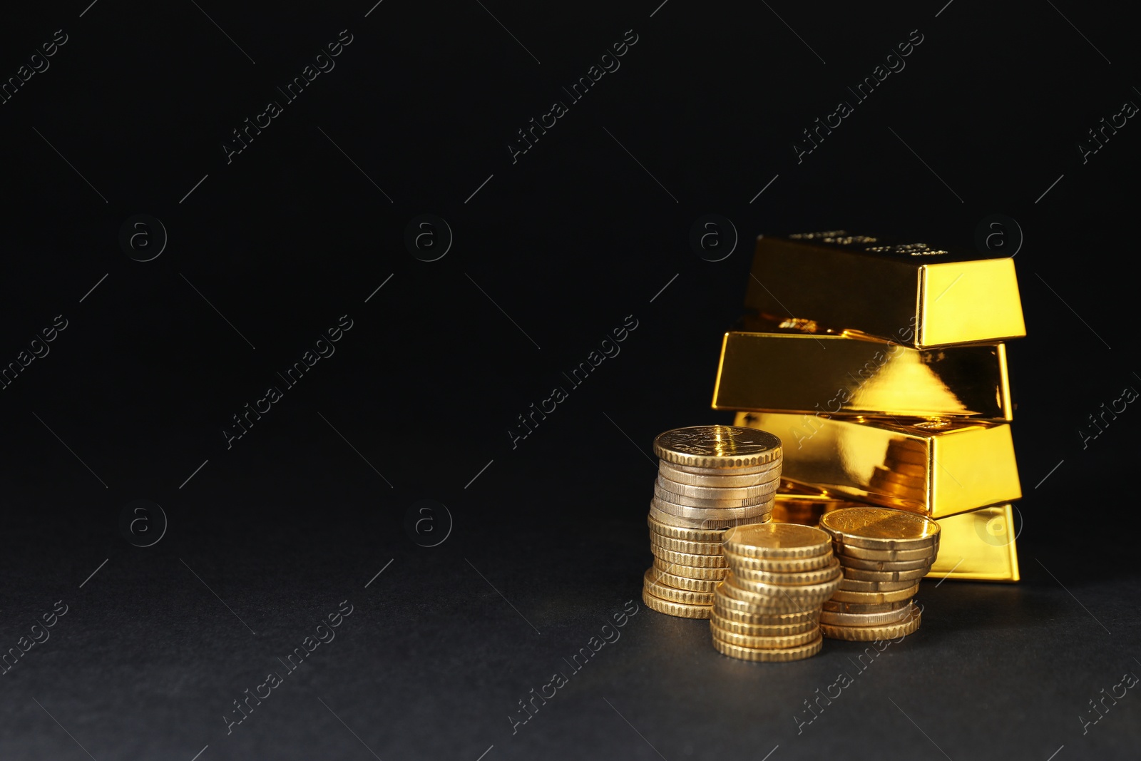 Photo of Gold bars and coins on black table, space for text