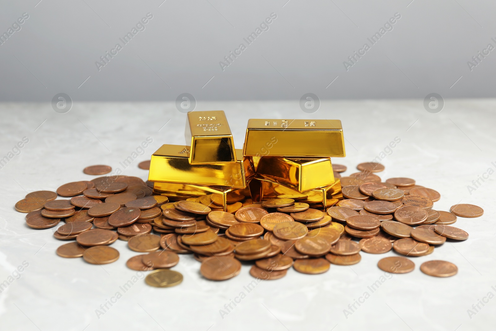 Photo of Gold bars and coins on grey marble table, closeup