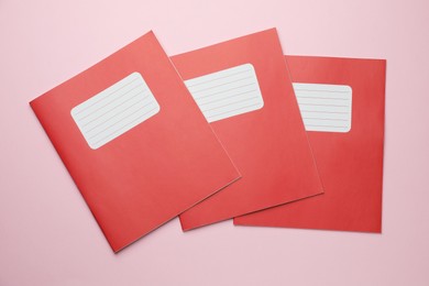 Photo of Colorful copybooks on pink background, flat lay. School stationery