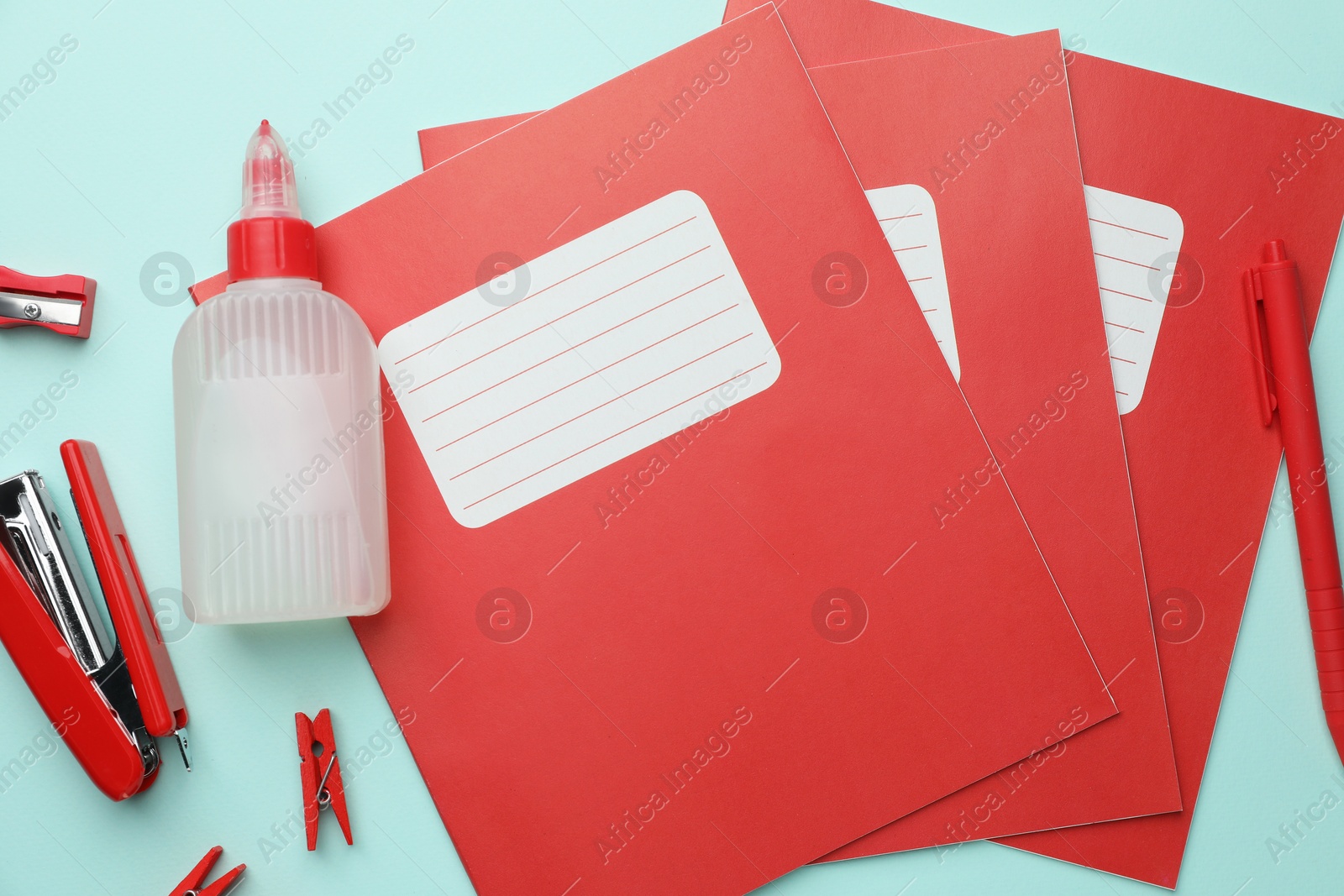 Photo of Copybooks and other school stationery on light blue background, flat lay