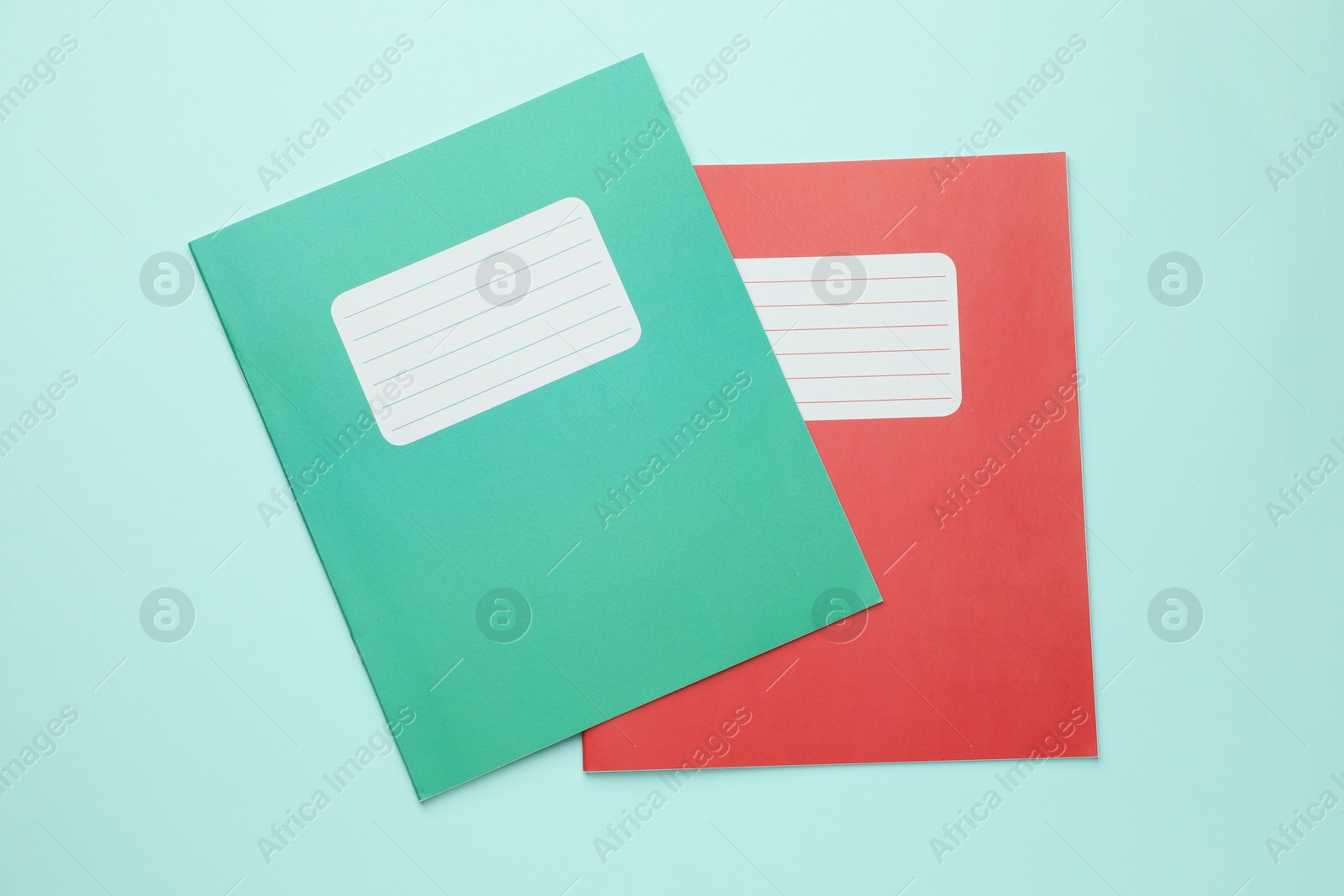 Photo of Colorful copybooks on light blue background, top view. School stationery