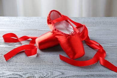 Photo of Pair of red pointe shoes on grey wooden table