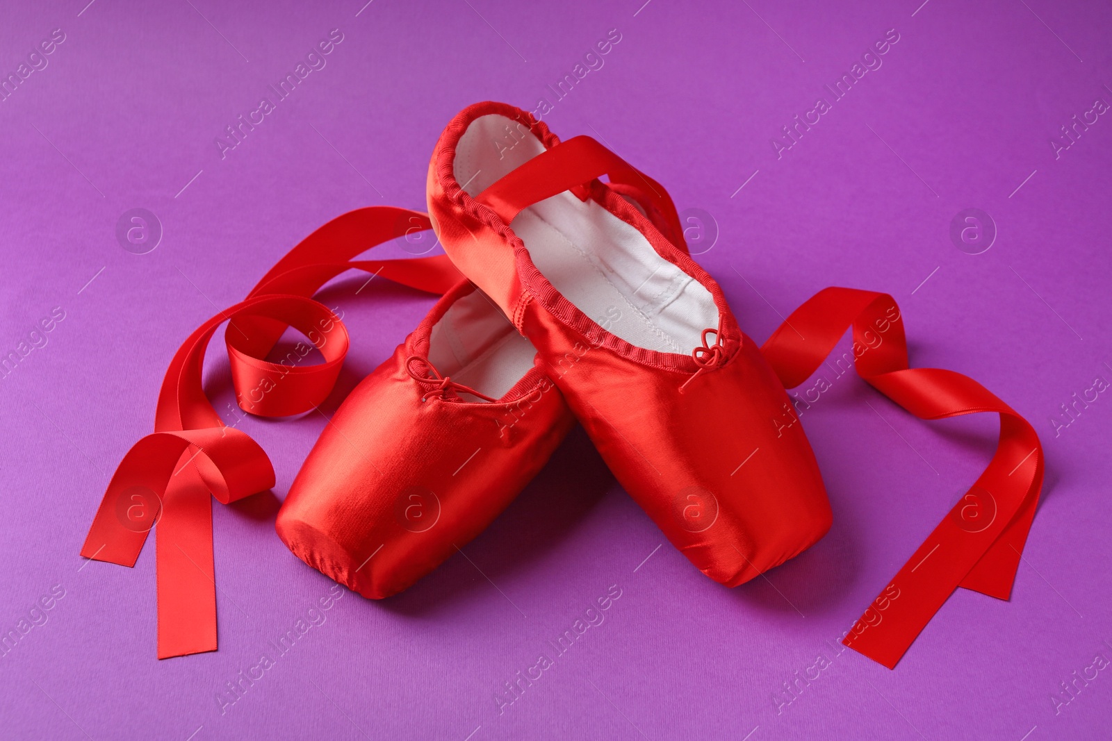 Photo of Pair of red pointe shoes on purple background