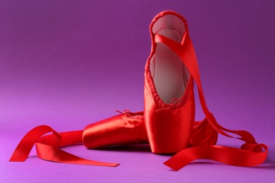 Photo of Pair of red pointe shoes on purple background