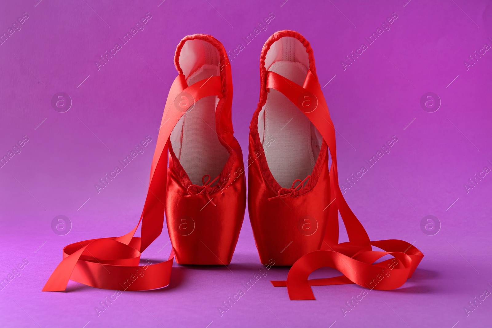 Photo of Pair of red pointe shoes on purple background