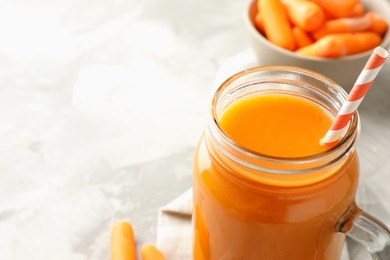 Photo of Fresh carrot juice in mason jar on gray table, closeup. Space for text