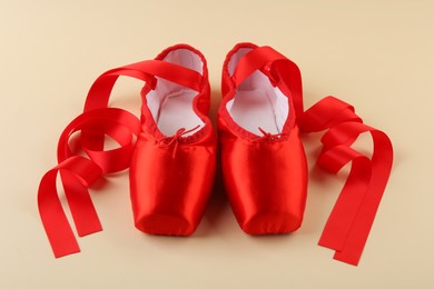 Photo of Pair of red pointe shoes on beige background