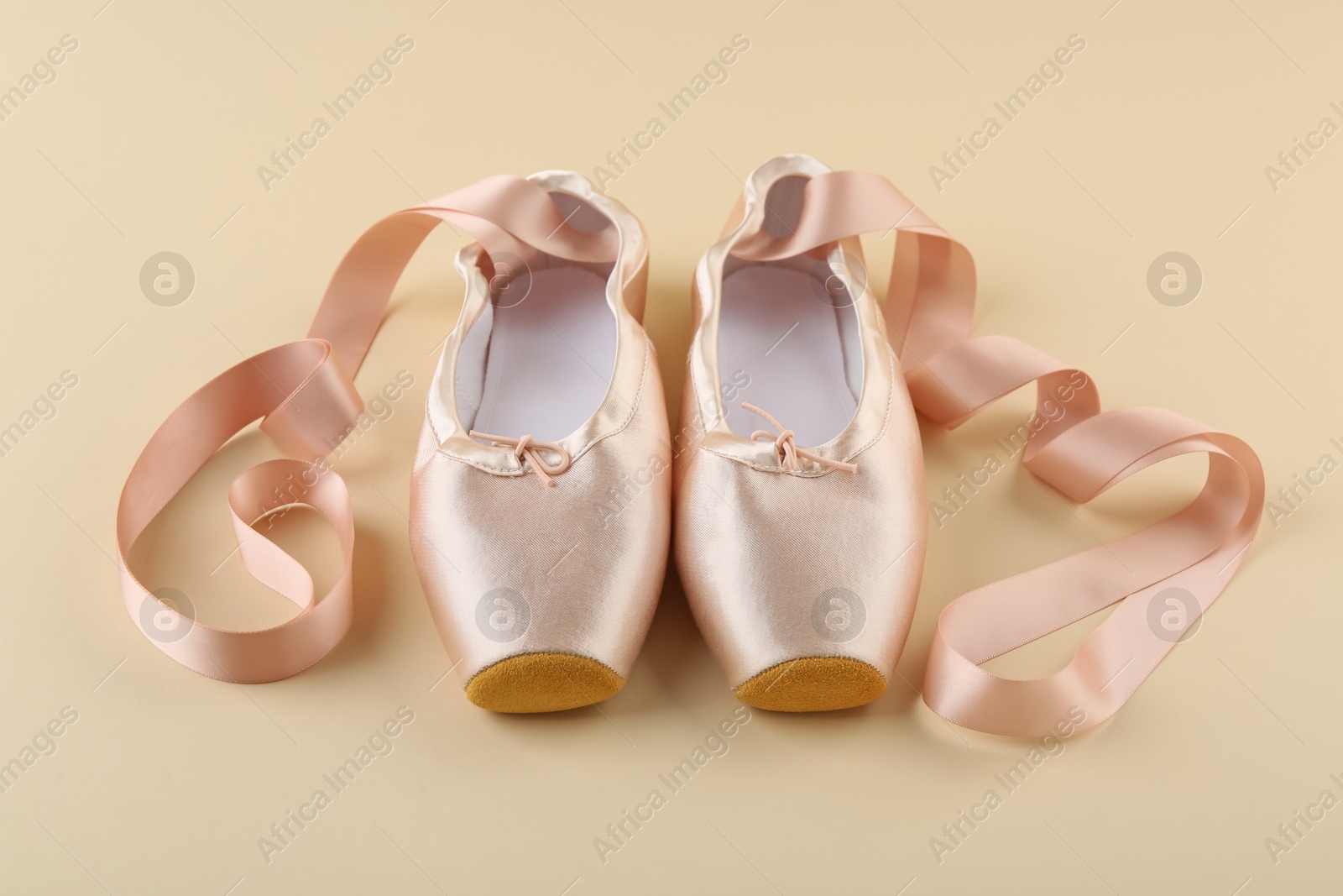 Photo of Pair of beautiful pointe shoes on beige background