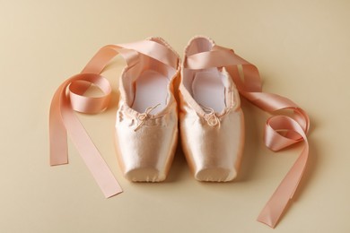 Photo of Pair of beautiful pointe shoes on beige background