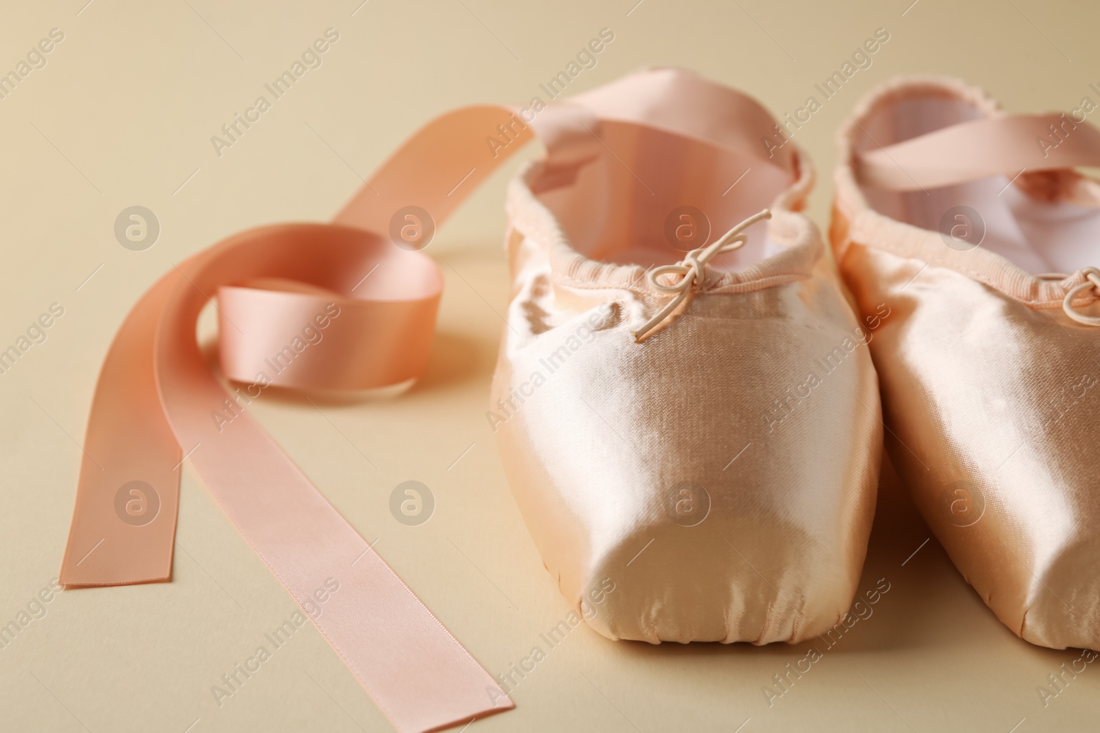 Photo of Pair of beautiful pointe shoes on beige background, closeup