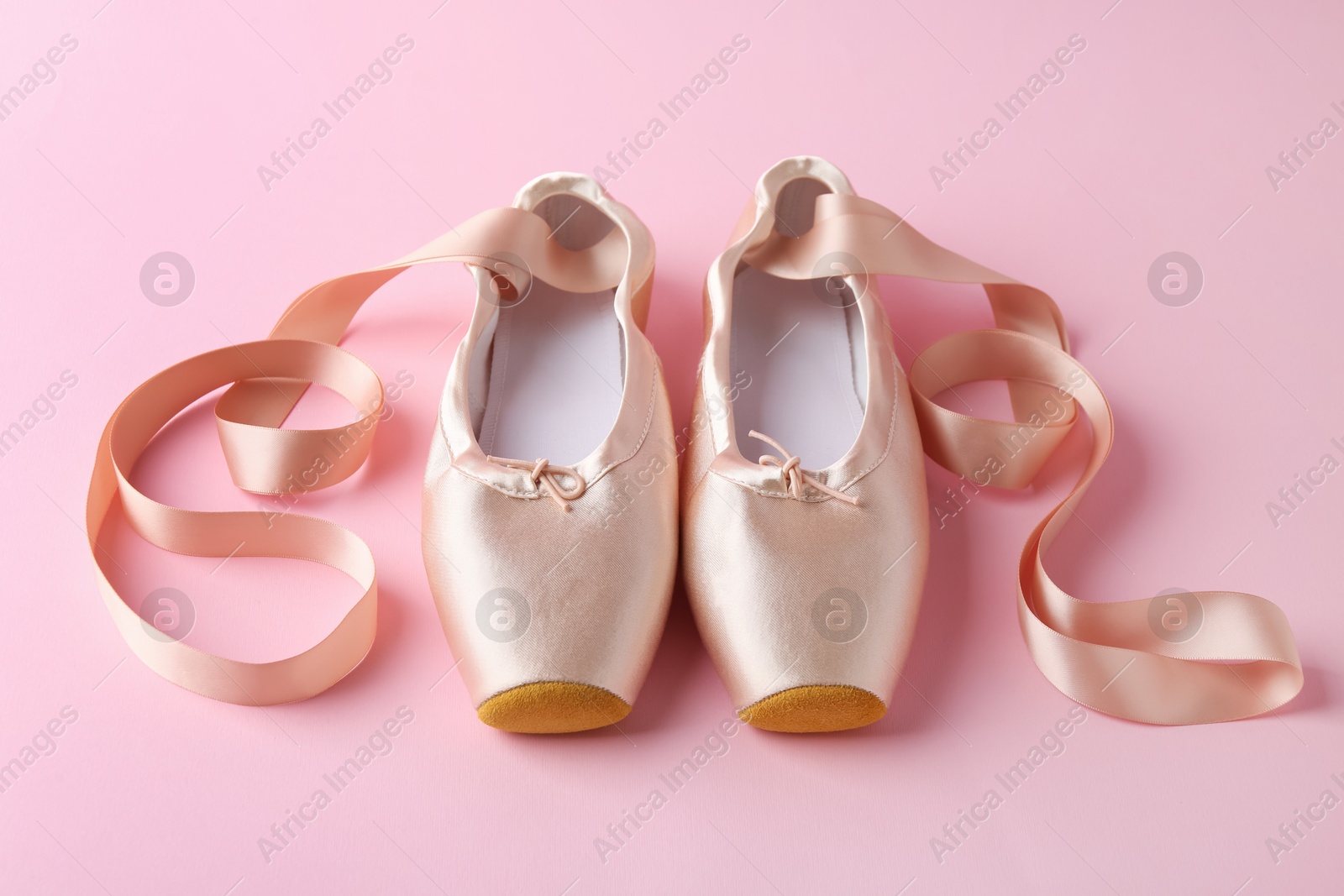 Photo of Pair of beautiful pointe shoes on pink background