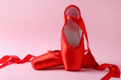 Photo of Pair of beautiful red pointe shoes on pink background