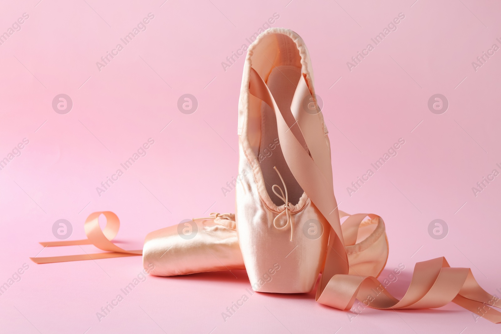 Photo of Pair of beautiful pointe shoes on pink background