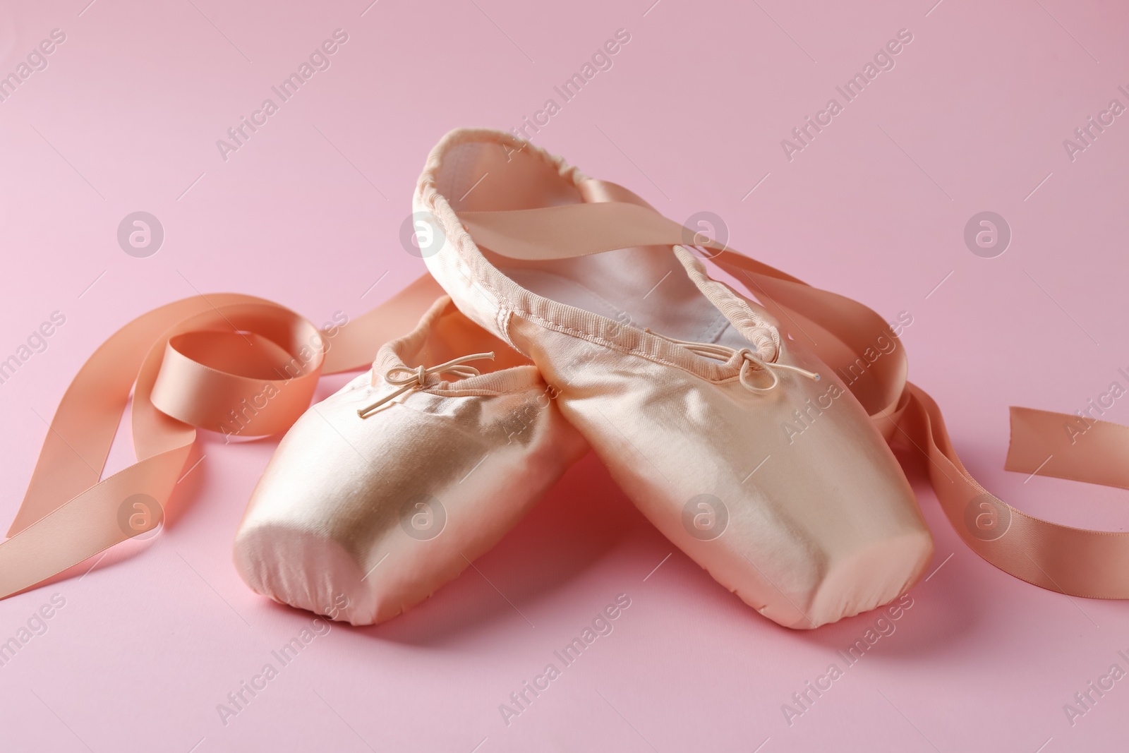 Photo of Pair of beautiful pointe shoes on pink background