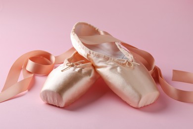 Photo of Pair of beautiful pointe shoes on pink background