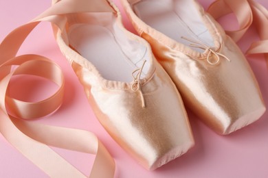 Photo of Pair of beautiful pointe shoes on pink background, closeup