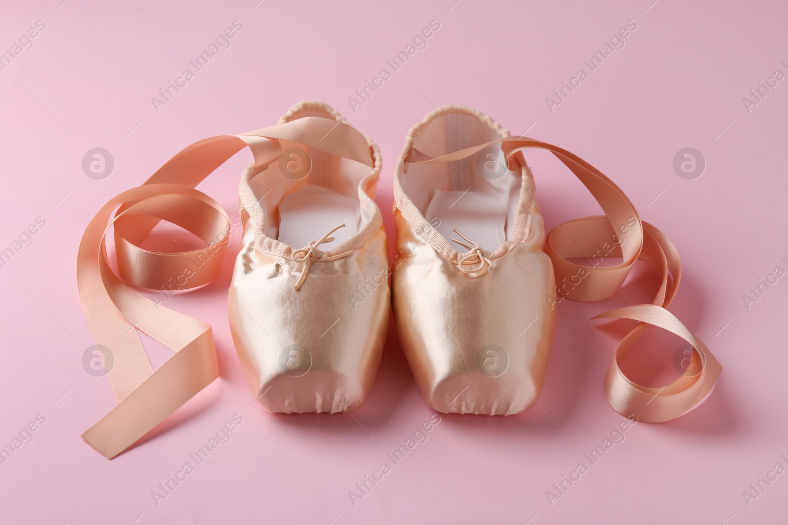 Photo of Pair of beautiful pointe shoes on pink background