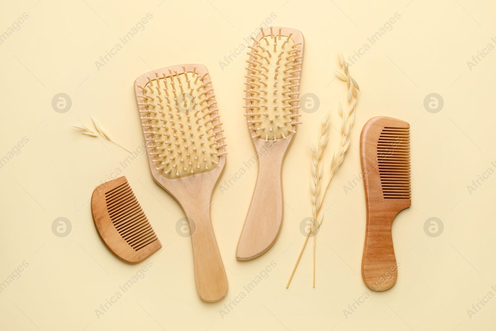 Photo of Wooden hair brushes, combs and spikes on beige background, flat lay