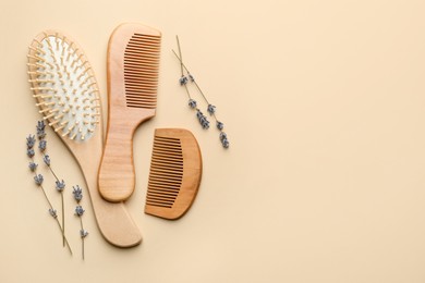 Photo of Wooden hair brush, combs and lavender flowers on beige background, flat lay. Space for text