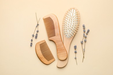 Photo of Wooden hair brush, combs and lavender flowers on beige background, flat lay