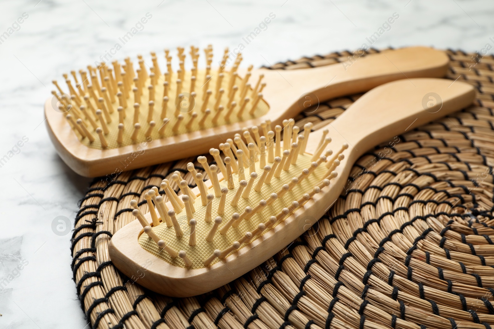 Photo of Wooden hair brushes on white marble background, closeup