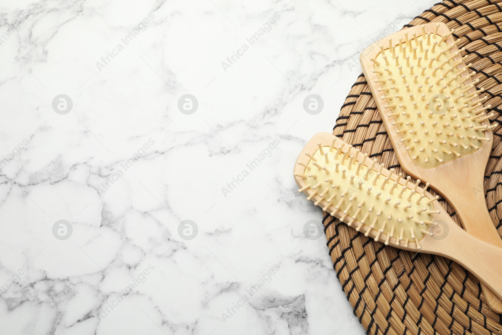 Photo of Wooden hair brushes on white marble background, top view. Space for text