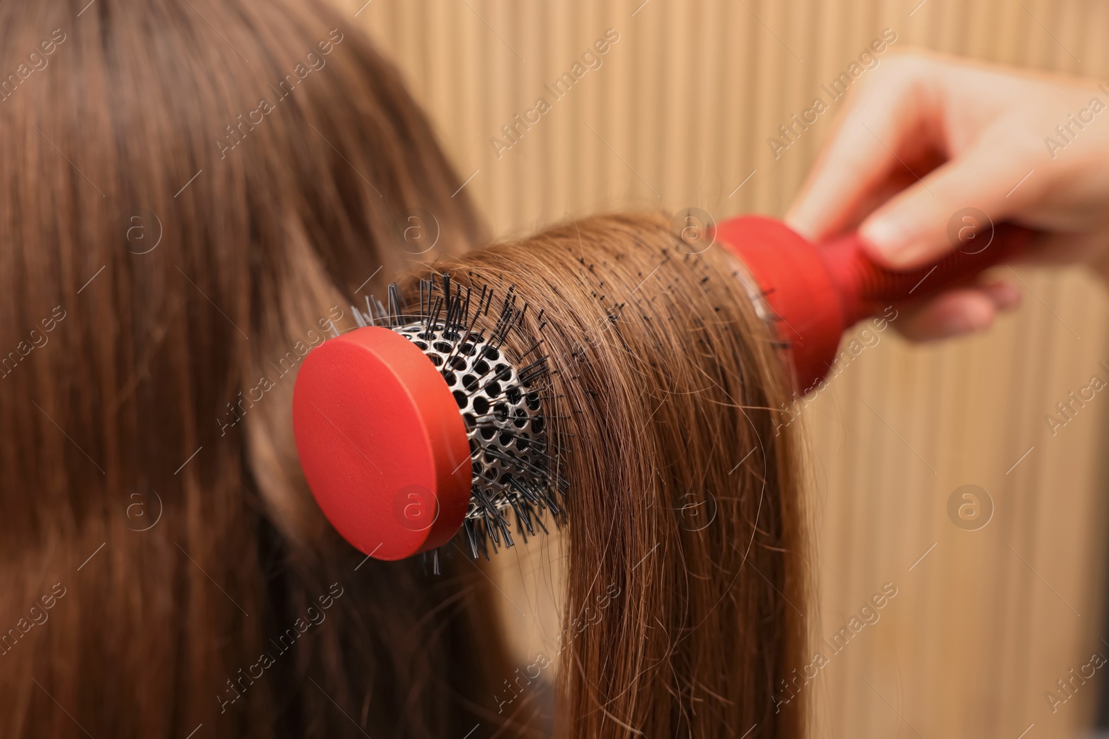 Photo of Hairdresser styling client's hair with round brush in salon, closeup